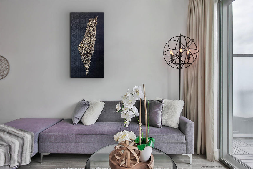 Palestine map in Diwani calligraphy using the names of its cities, with Palestinian tatreez–inspired embroidery in a living room.