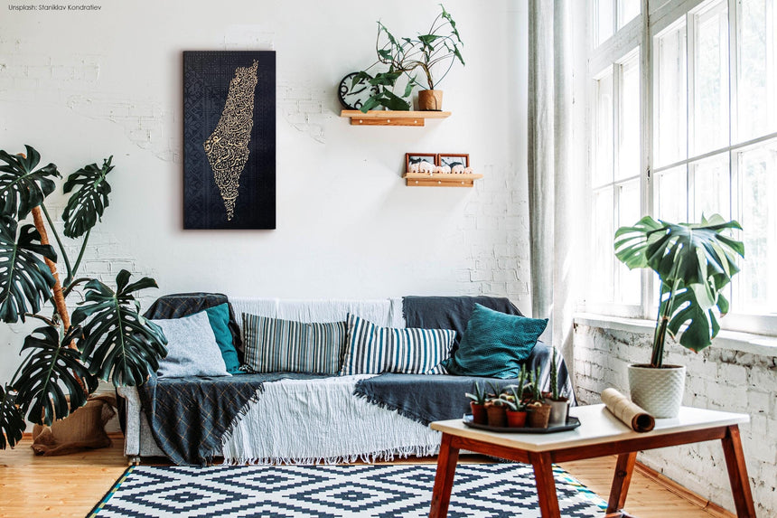 Palestine map in Diwani calligraphy using the names of its cities, with Palestinian tatreez–inspired embroidery in a living room.