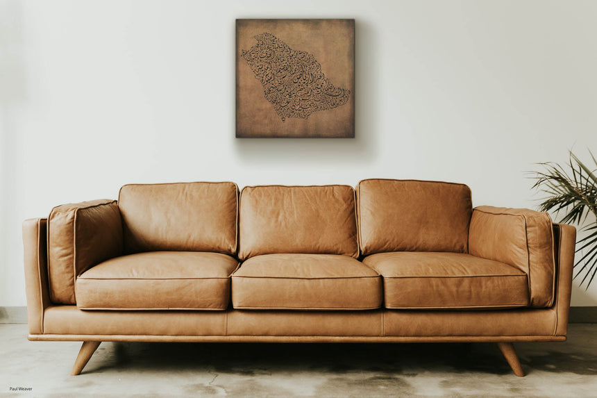 Carved wood artwork of the Saudi Arabia map, drawn in Diwani calligraphy using the names of its cities, in a living room setting